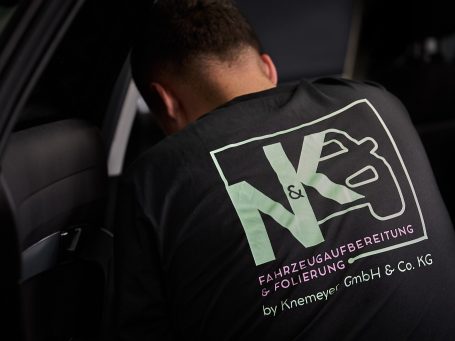 Person in einem T-Shirt mit Logo und Text über Fahrzeugtuning.