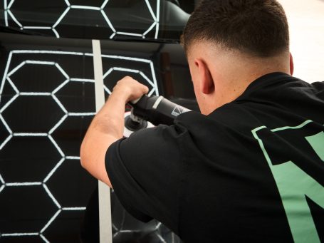 Junger Mann bearbeitet eine Fläche mit hexagonalem Muster und Werkzeug.
