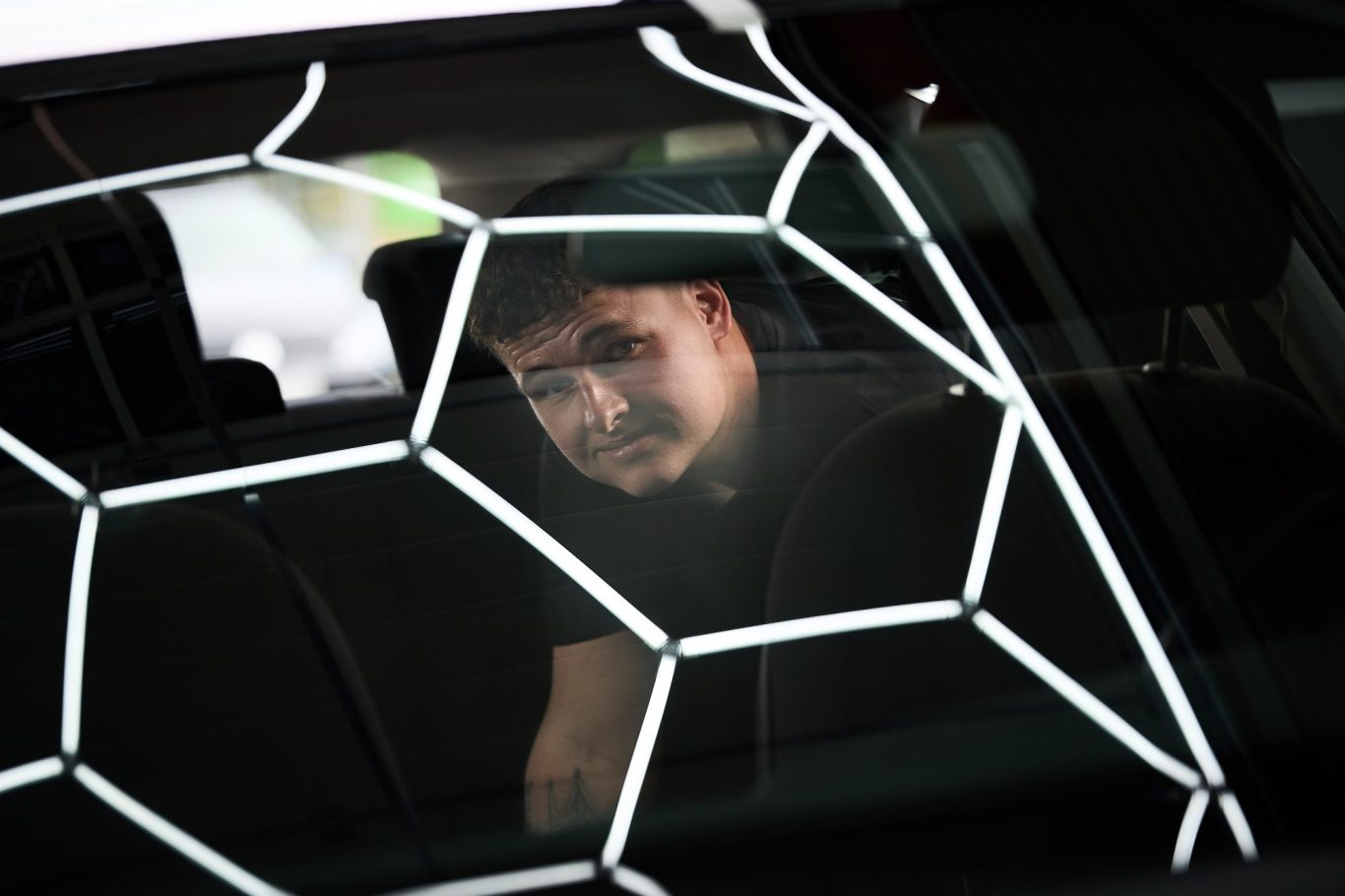 Junger Mann hinter einem Fenster mit hexagonalem Muster.